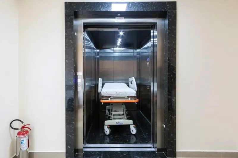Elevador hospitalar com maca em corredor