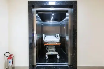 Elevador hospitalar com maca em corredor