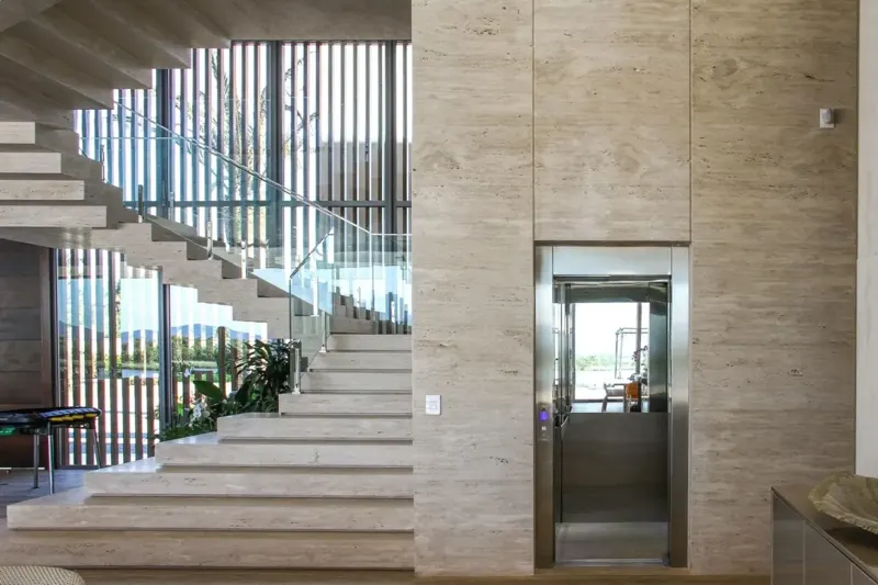 Elevador predial em hall com escada de mármore