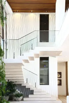 Elevador residencial ao lado de escada em mármore